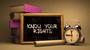 Know Your Rights Handwritten on Chalkboard. Time Concept. Composition with Chalkboard and Stack of Books, Alarm Clock and Scrolls on Blurred Background. Toned Image.